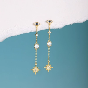 Detailed view of long gold tassel earrings featuring devil eye and sunburst crystal charms
