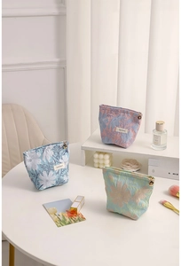 Detailed view of floral jacquard cosmetic bags with unique petal-shaped metal zippers