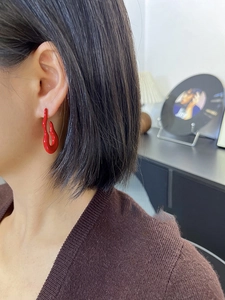 Close-up of vibrant red irregular fluid lava earrings on model for a modern look