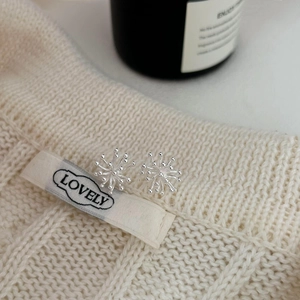 Minimalist 925 sterling silver snowflake earrings displayed on a white knitted sweater