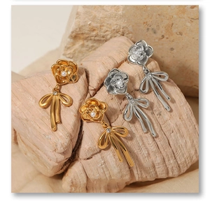 Détail de boucles d'oreilles rose et nœud avec perles et cristaux en or et argent
