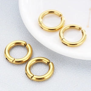 Polished golden stainless steel non-pierced hoop earrings on a ceramic dish and table