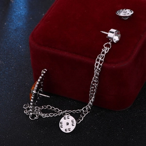 Detail of vintage silver square brooch with orange faceted gemstone and tassel chain