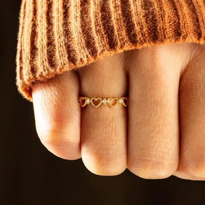 Bague cœur ajourée dorée avec cristaux étincelants sur fond en maille douce