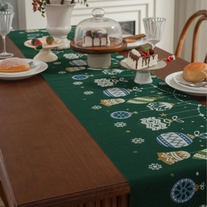 Detail of dark green Christmas table runner with festive snowflakes and bells patterns