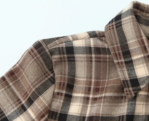 Gros plan sur les coutures de l'épaule et du col d'une chemise à carreaux marron
