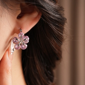 Gros plan de boucles d'oreilles fleur en zircon rose portées par un mannequin élégant
