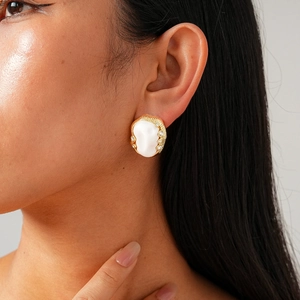 Macro detail of oval pearl earring with golden textured frame and sparkling side rhinestones