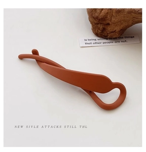 Detail of twisted caramel brown hair claw clip with matte finish on white background