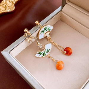 Close-up of ethnic style drop earrings with bamboo design and orange beads in jewelry box