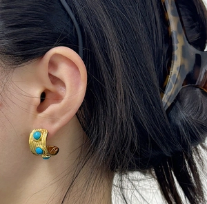 Gros plan de boucles d'oreilles créoles dorées texturées avec trois pierres turquoises