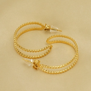 Detail of 18K gold-plated double-loop beaded hoop earrings on beige textured fabric