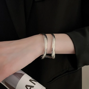Detail of silver geometric double-layered open cuff bracelet on a model wrist