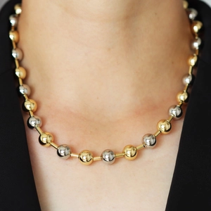 Polished gold and silver mixed beaded necklace on a model wearing black suit