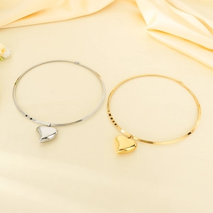 Polished gold and silver hollow heart pendant collars on elegant silk fabric