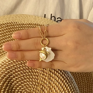Golden starfish and dolphin pendant necklace featuring a white shell charm on hand