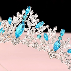 Detailed view of silver crown with blue crystal leaves and sparkling rhinestones