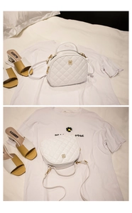 Detailed macro view of white quilted PU leather handbag with gold clover logo hardware