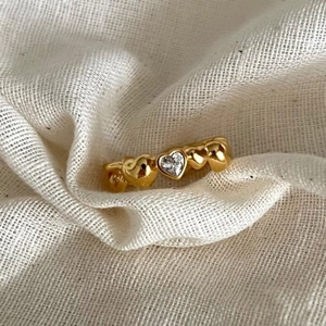 Golden 925 sterling silver heart ring with zircon stone on soft white fabric background