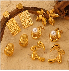 Vue à plat de boucles d'oreilles vintage en acier titane doré et perles sur fond pierre