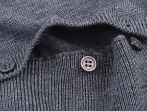 Gros plan sur un pull en maille gris foncé avec boutons ronds et texture côtelée
