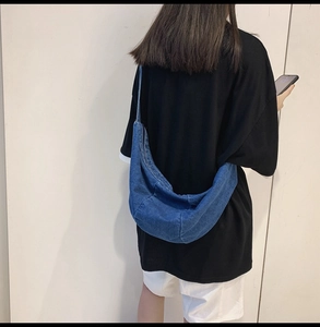 Back view of a person wearing a denim blue crescent crossbody bag for casual daily use