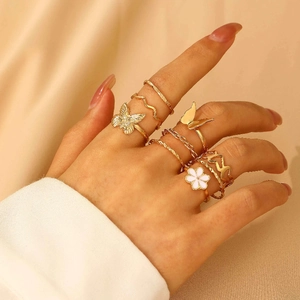 Detailed close-up of gold vintage floral and butterfly rings set on wrinkled fabric