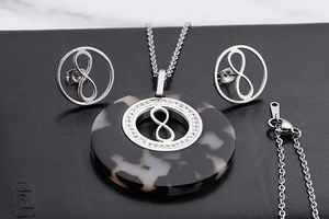 Close-up of infinity symbol necklace and earrings set with marble pattern resin