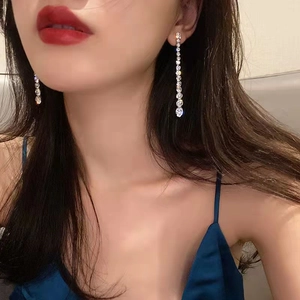 Close-up of sparkling silver tassel earrings with multiple rhinestones worn by a model