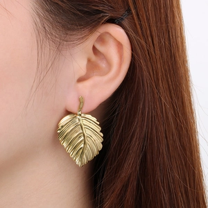 Close-up of leaf-shaped gold earrings showing realistic veins and metallic texture