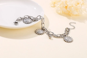 Detail of a silver sun pendant on a layered titanium steel chain with lobster clasp
