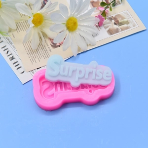 Moule en silicone rose pour lettrage Surprise avec produit fini bleu sur fond bleu
