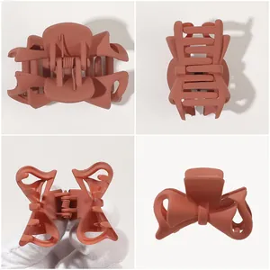 Detail view of large matte terracotta bow claw clip with metal spring and hollow design