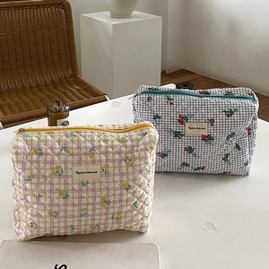 Quilted floral makeup bags in yellow and blue plaid with flower patterns on a desk