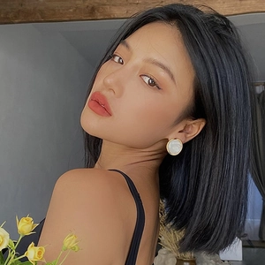 Close-up of model wearing round white resin earrings with elegant gold metal frames