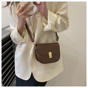 Detail of vintage brown saddle bag with golden clasp and adjustable shoulder strap