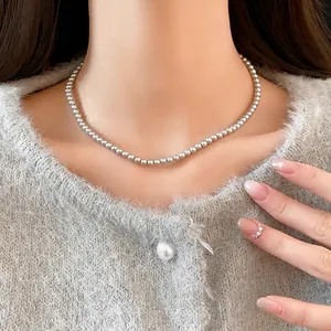Elegant minimalist white pearl choker necklace for women worn with grey cardigan