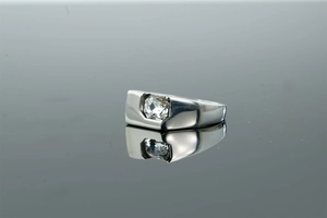 Macro shot of silver signet ring featuring a rectangular zircon stone on mirror surface
