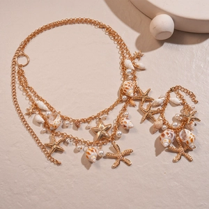 Bohemian gold layered starfish and seashell necklace with pearls on beige surface