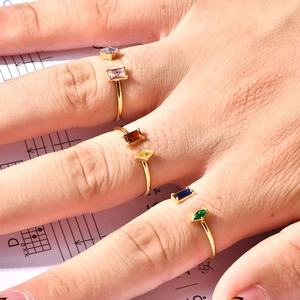Detailed close-up of adjustable gold-plated rings with colorful rectangular crystals