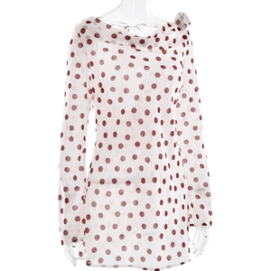 Detail of red polka dot dress featuring a high pleated neck and 3D fabric flower on shoulder