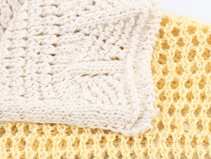 Close-up of delicate hollow mesh knit fabric in cream and soft yellow tones