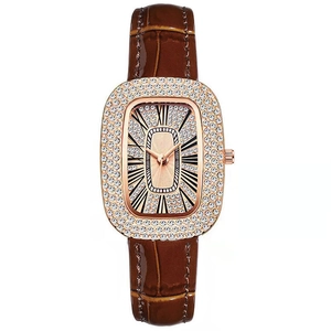 Close-up of rose gold rhinestone watch with brown leather strap and crystal dial