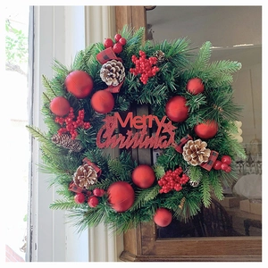 Detail eines Weihnachtskranzes mit Kiefernnadeln, roten Beeren und Merry Christmas Schild