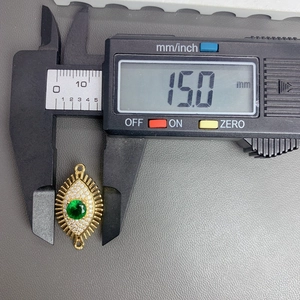 Macro shot of gold devil eye charm measured with digital calipers showing 15.0mm size