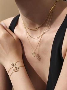 Close-up of gold clover necklace and bracelet set with sparkling crystals on a model