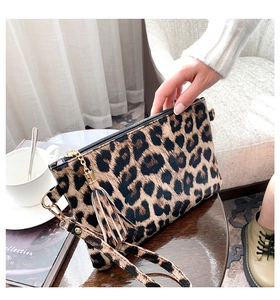 Leopard print clutch bag with gold tassel detail on a wooden table setup