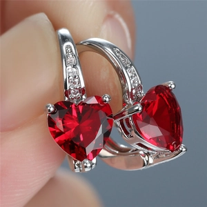 Macro shot of silver stud earring with heart-cut red gemstone and clear accents