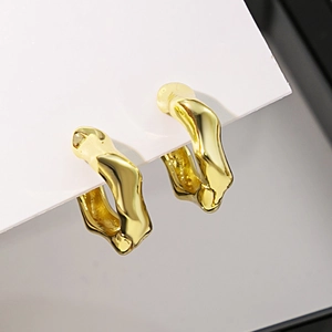 Vue macro de boucles d'oreilles dorées irrégulières avec texture métal poli
