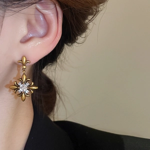 Close-up of vintage gold iris flower earrings with sparkling zircons worn by a model